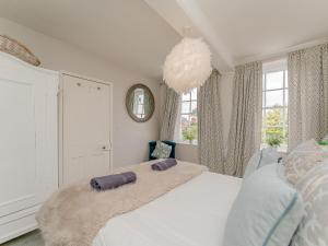 Un dormitorio con una cama blanca con almohadas moradas. en Ivy Cottage, en Chester