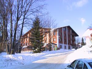 una calle cubierta de nieve con un edificio y un árbol de Navidad en Apartement Hrebenka en Harrachov