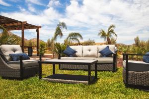 a patio with a couch and two chairs on the grass at Indomito Resort & Hotel Boutique in Valle de Guadalupe