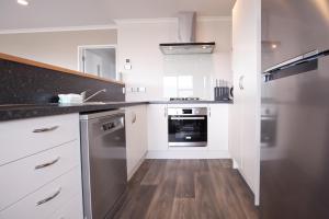 a kitchen with white cabinets and stainless steel appliances at Ashley Heights in Lake Tekapo