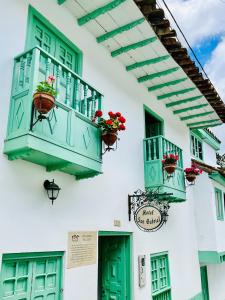 ein weißes Gebäude mit grünen Fenstern und Blumenkästen in der Unterkunft Hotel San Gabriel in El Cocuy