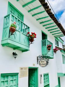 un edificio bianco con finestre verdi e fioriere di Hotel San Gabriel a El Cocuy