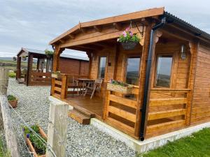 a wooden cabin with a deck and a table at Harlosh Log Cabins in Dunvegan