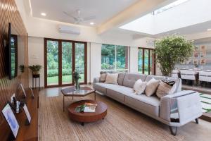 a living room with a couch and a table at Prism and Palette by StayVista - Nestled amidst greenery, offering vibrant interiors, a swimming pool, snooker table, gazebo, and a spacious lawn area in Alibaug