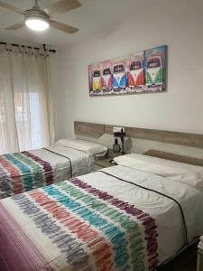 two beds in a room with a painting on the wall at SOLYMAR PONIENTE Apartamento Recién Reformado A 3 min de Playa Poniente y del Centro Parking Opcional in Benidorm