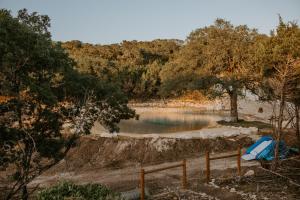 a body of water with trees and a fence at Hummingbird Haus - Hill country views on 20 acres with firepit in Spring Branch +20 photos