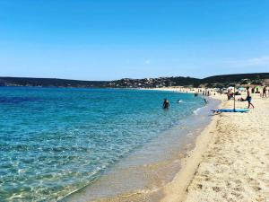 a beach with a group of people in the water at Le Dune Dorate in Torre Dei Corsari +10 photos