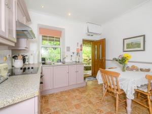 a kitchen with white cabinets and a table with chairs at Tor View Fourwinds in Okehampton
