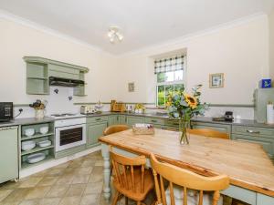 a kitchen with a wooden table with a vase of flowers at Brokan Fourwinds in Okehampton