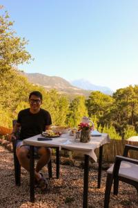 un hombre sentado en una mesa con comida. en EvergreenGlamping en Kumluca