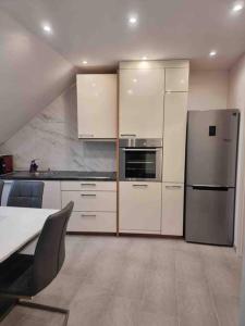 a kitchen with white cabinets and a stainless steel refrigerator at Apartment near Bonn/Cologne with nature access in Troisdorf