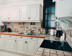 a kitchen with white cabinets and a sink at AcropolisCozyStay in Athens