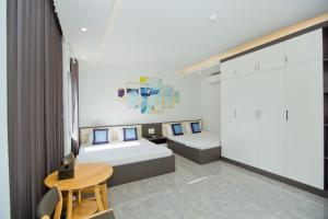 een kamer met 2 bedden, een tafel en een bureau bij King House Hotel in Móng Cái