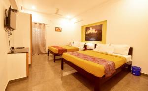 Habitación de hotel con 2 camas y TV en BHARATHI RESIDHOME en Pondicherry