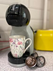 a coffee maker with a coffee cup on a counter at Venta apartament in Mažeikiai +6 photos