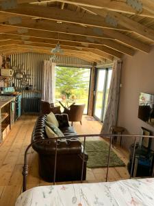 a living room with a leather couch and a large window at Byre Cottages & Log Cabin in Cardigan