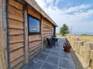 a wooden cabin with a patio and a window at Byre Cottages & Log Cabin in Cardigan