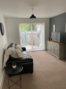 sala de estar con sofá de cuero negro y mesa en Springfield Retreat, en Risca