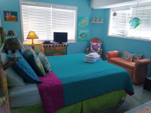 a blue bedroom with a bed and a chair at A18 Parrot Escape - OCEAN VIEW! There is nothing quite like a Carolina sunrise viewed from your private oceanfront deck condo in Carolina Beach