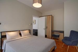 a bedroom with a bed and a blue chair at MAHE APARTMENT in Volos