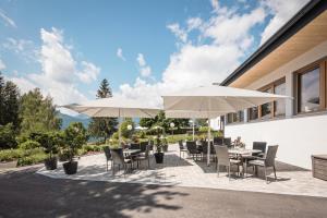 eine Terrasse mit Tischen, Stühlen und Sonnenschirmen in der Unterkunft Naturhotel Landhof Irschen in Irschen