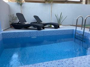 a swimming pool with a pair of chairs next to it at Voula Hotel in Hersonissos