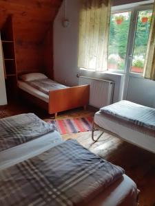 a room with two beds and two windows at Cabana Valea Stanciului in Răchiţele