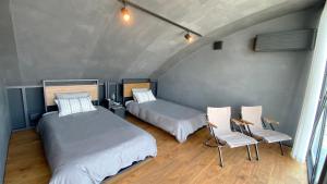 横須賀市にあるYokosuka Sky Grey -横須賀-のベッド2台と椅子2脚が備わる客室です。