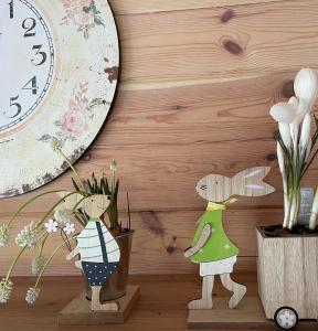 two wooden figurines sitting next to a clock and flowers at Ragaciema Skadiņi in Ragaciems