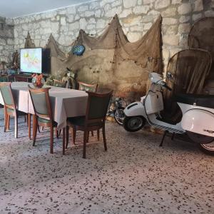 skuter motorowy zaparkowany obok stołu i krzeseł w obiekcie Guesthouse Lidija w mieście Sutivan