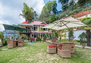 eine Gruppe von Stühlen und Tischen mit Sonnenschirmen in der Unterkunft Udaan Nirvana Resort, Darjeeling in Darjeeling