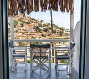 a table and chairs on a balcony with a view of a hill at Pavezzo in Ios Chora