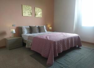 a bedroom with a bed with a pink blanket and a window at Casa Angelica in Plesio