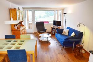 a living room with a blue couch and chairs and a table at Tgesa Sunnmatt 24 in Savognin