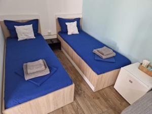 two beds in a room with blue sheets and towels at Pagini Din Vama in Vama Veche