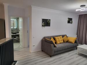 - un salon avec un canapé gris et des oreillers jaunes dans l'établissement Dacrilo Apartments Cluj-Napoca 11, à Cluj-Napoca