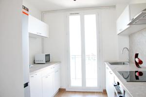 eine weiße Küche mit weißen Schränken und einem Fenster in der Unterkunft T4 Pro Groupes - 5min Airbus - 6pers - Parking in Colomiers