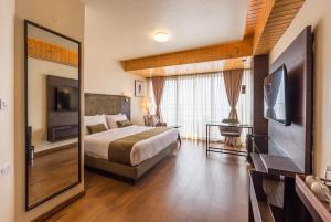 ein Hotelzimmer mit einem Bett und einem großen Spiegel in der Unterkunft Udaan Himalayan Suites and Spa in Darjeeling