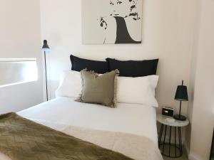 1 dormitorio con 1 cama con sábanas y almohadas blancas en Harbour Escape Apartments Docklands, en Melbourne