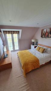 a bedroom with a large bed with a yellow blanket at Charming Lake House nature retreat in Cotswold Water Park, South Cerney near Cirencester in Cirencester