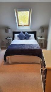 a bedroom with a bed with blue pillows and a window at Charming Lake House nature retreat in Cotswold Water Park, South Cerney near Cirencester in Cirencester