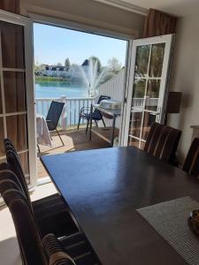 a dining room table with a view of the water at Charming Lake House nature retreat in Cotswold Water Park, South Cerney near Cirencester in Cirencester