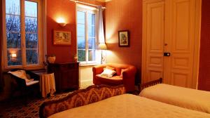 a bedroom with two beds and a chair and a window at Les Volets Bleus in Sallèles-dʼAude