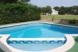 una piscina con un banco al lado en Es Pins, en Cala Blanca