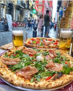 due pizze su un tavolo con due bicchieri di birra di Fondaco House a Napoli