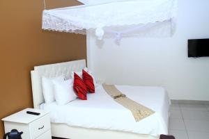 a bedroom with a white bed with red pillows at Garden Courts Hotel Masaka in Masaka