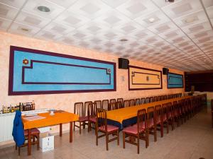 une salle à manger avec des tables, des chaises et un grand écran dans l'établissement Hostal La Maravillosa, à Valderas