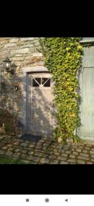 una puerta a un edificio con una hiedra creciendo en él en A la Grange d'en Haut, en Bras-Haut