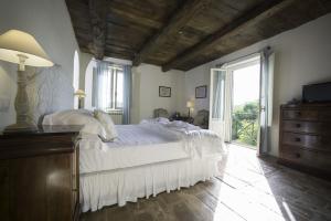 um quarto com uma cama branca e uma grande janela em Tenuta Santo Pietro em Pienza