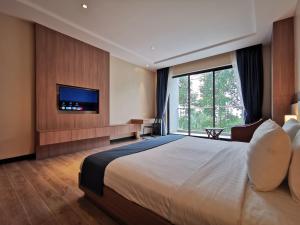 um quarto de hotel com uma cama grande e uma televisão de ecrã plano em RIVA Hotel SHV em Sihanoukville